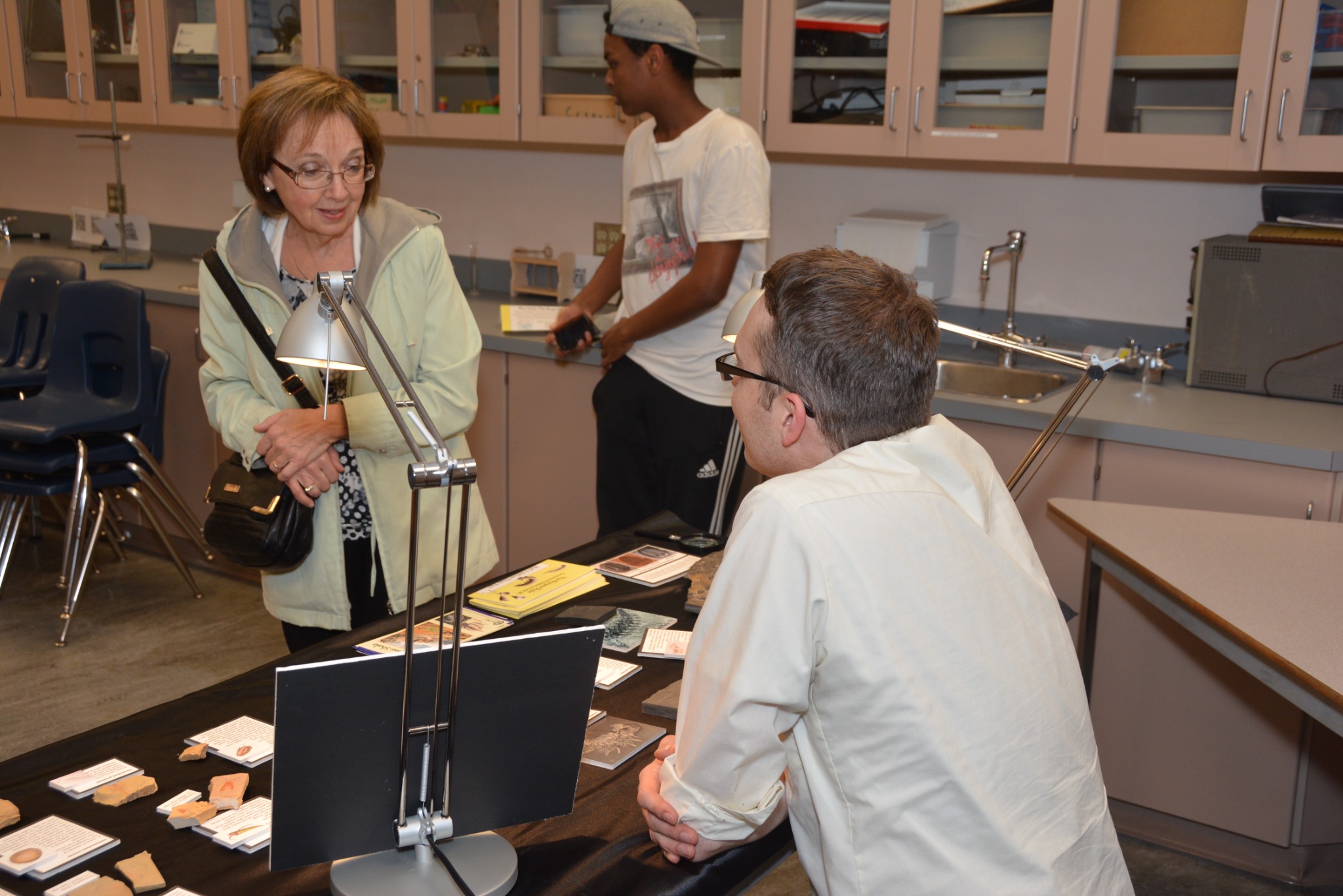 A visitor speaking with a volunteer at a Burgess Shale Nights fossil display